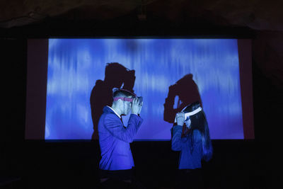 Male and female entrepreneurs wearing futuristic glasses in illuminated convention center