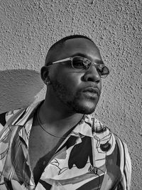 Portrait of young man wearing sunglasses against wall