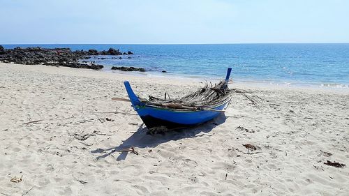 Boat moored on beach against sky