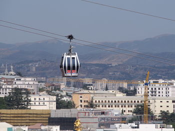 Overhead cable car in city against sky