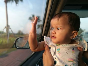 Cute baby girl looking through window in car