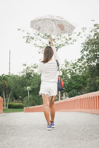 Rear view of woman walking with umbrella
