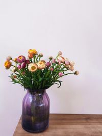 Flowers in vase on table against wall