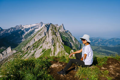 Man sitting on rock against mountains