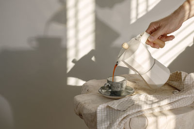 Close-up of hand pouring tea cup