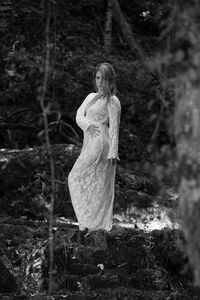 Portrait of young woman standing at river in forest