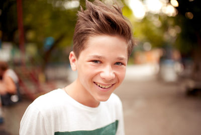 Smiling kid boy with stylish hairstyle outdoors. looking at camera. teenage boy