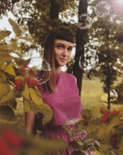 Portrait of beautiful woman standing by flower tree