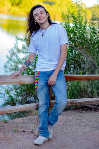 Portrait of teenage boy standing against plants near lake