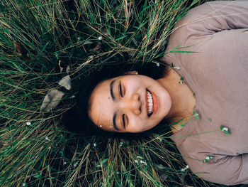 Portrait of young woman lying down on grass