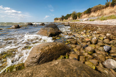 Surface level of rocks on shore against sky