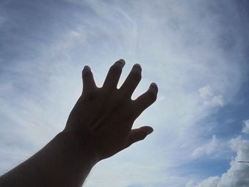 Cropped hand reaching sky