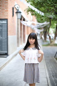 Portrait of a smiling girl standing against building