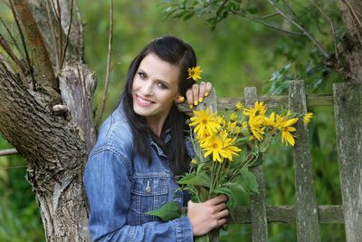 Portrait of smiling young woman against trees