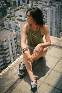 Full length of woman sitting against buildings in city