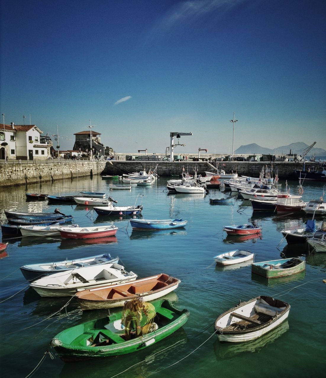 nautical vessel, moored, transportation, boat, mode of transport, water, harbor, building exterior, sea, built structure, architecture, mast, sky, clear sky, blue, waterfront, sailboat, outdoors, day, travel