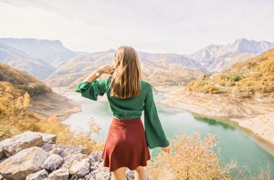 Rear view of woman standing on cliff against sky