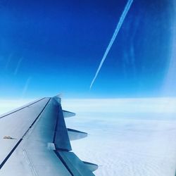 Airplane flying over sea against blue sky