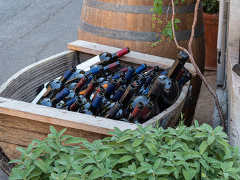 Empty wine bottles stacked in a wooden container near a wine barrel.