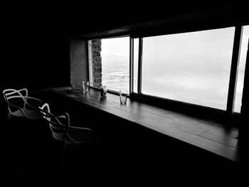 Empty chairs and table by window