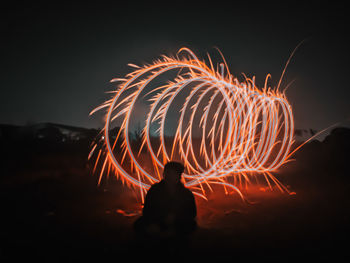 Low angle view of woman holding sparkler at night