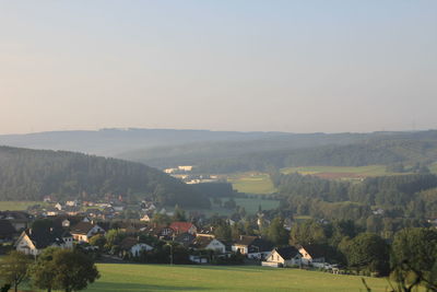 Scenic view of field by houses against clear sky