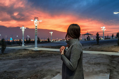 Woman standing on beach against sky during sunset