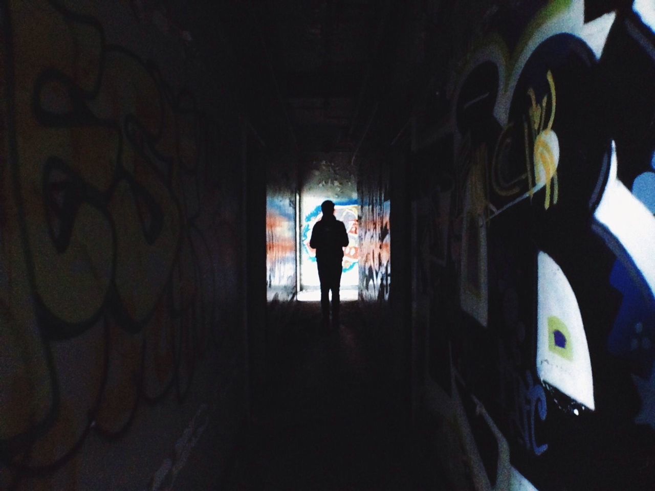 indoors, architecture, tunnel, built structure, wall - building feature, full length, lifestyles, rear view, men, graffiti, silhouette, walking, wall, standing, arch, corridor, the way forward, building