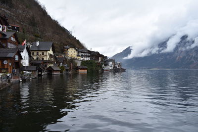 Houses by lake and buildings against sky