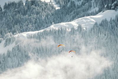 People flying over snowcapped mountain