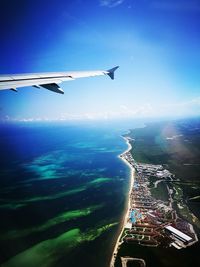 Aerial view of airplane flying over sea against blue sky