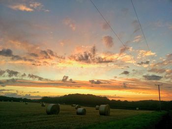 Hay bales on field against sky during sunset