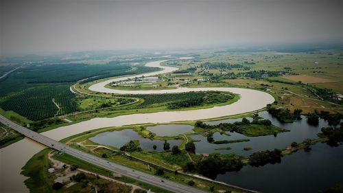 High angle view of river amidst field against sky