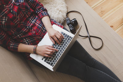 Midsection of woman using laptop while resting on sofa at home