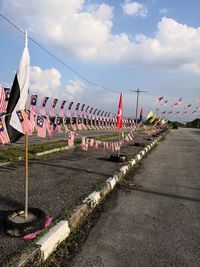 Row of flags hanging on road against sky