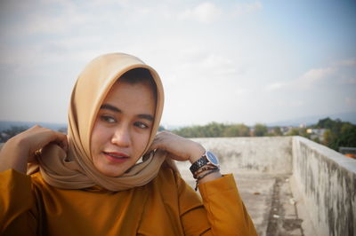 Portrait of young woman standing against sky