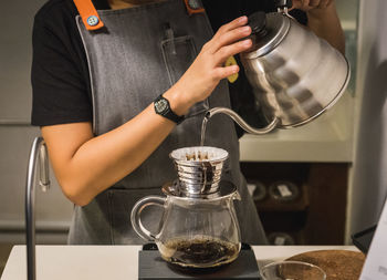 Midsection of woman pouring coffee in cup