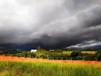 Scenic view of field against storm clouds