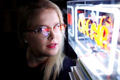 Smiling young woman looking at neon lights