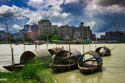 Boats moored in river against buildings in city