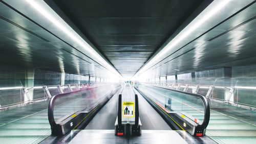 Empty moving walkway in illuminated subway station