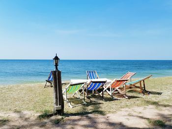 Chairs on beach against blue sky