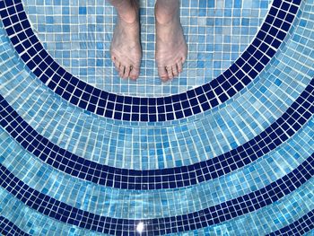 Low section of man standing in swimming pool