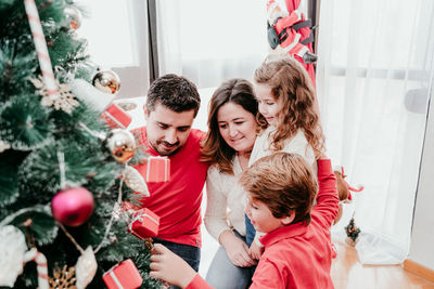 Family decorating christmas tree at home