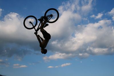 Low angle view of man jumping bicycle against sky