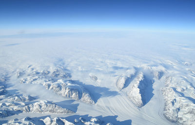 Aerial view of snowcapped landscape against blue sky