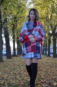 Portrait of young woman standing in park during autumn