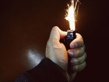 Close-up of hand holding burning candle