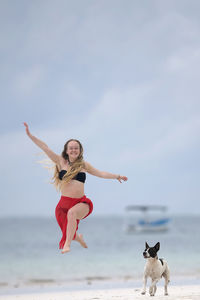 Full length of woman with dog on beach