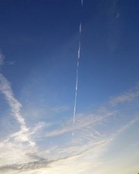 Low angle view of vapor trails in blue sky